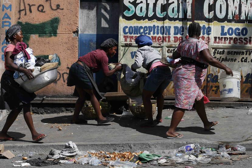 Vendedores recogen sus productos para resguardarse mientras se aproximan manifestantes que exigen la renuncia del presidente Jovenel Moïse en Puerto Príncipe, Haití, el lunes 21 de octubre de 2019. (AP/Rebecca Blackwell)
