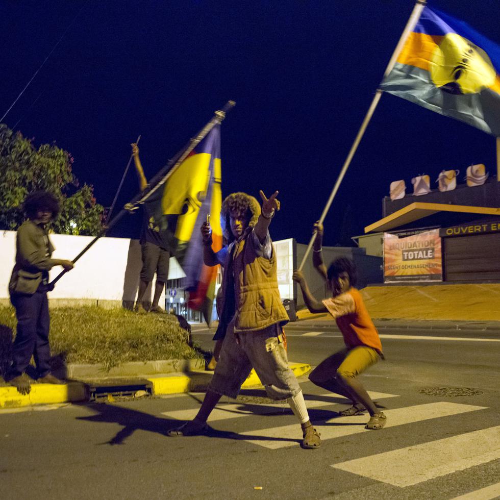 ARCHIVO - En esta fotografía de archivo del 4 de noviembre de 2018, activistas independentistas celebran en las calles de Numea, capital de Nueva Caledonia, mientras ondean la bandera indígena de los kanaks. (AP Foto/Mathurin Derel, archivo)