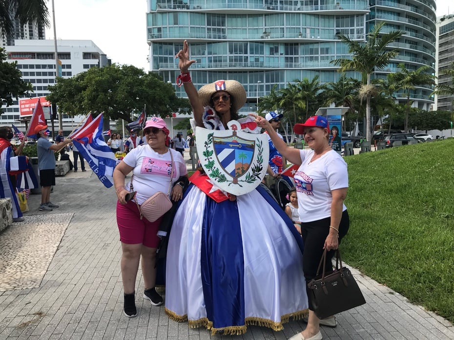 A woman in mambisa attire waits for the passage of a caravan of vehicles in support of the civic march for change in Cuba, in Miami.