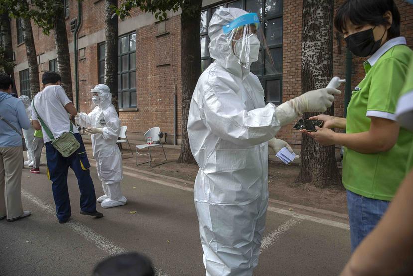Personal en trajes protectores realizan pruebas de COVID-19 a personas que pudieron haber estados expuestos a un brote del coronavirus en un mercado de comida en Beijing. (AP)