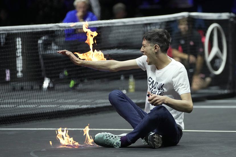 Un hombre se prende fuego en un brazo durante su protesta en el partido entre Diego Schwartzman y Stefanos Tsitsipas, en el evento de tenis Copa Laver en Londres, el viernes 23 de septiembre de 2022.