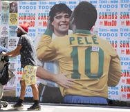 Un hombre empuja un carrito frente a un mural en el que se muestra al astro brasileño Pelé junto a la fallecida estrella del fútbol, el argentino Diego Maradona, en Sao Paulo, Brasil.