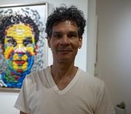 Nik Quijano frente a su obra "Auto retrato", trabajado con carritos plásticos creados por él o rescatados de la basura para hacer su autoretrato.
