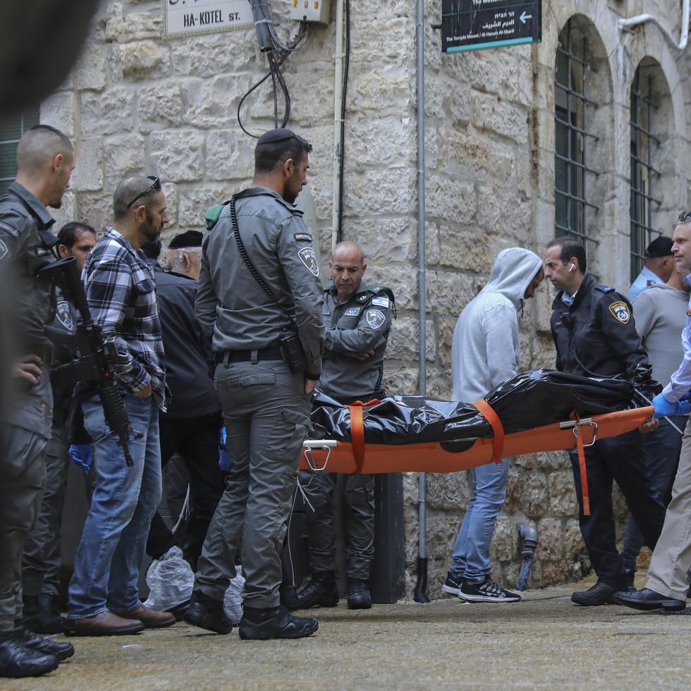 Personal de seguridad israelí traslada el cuerpo de un palestino baleado por la policía tras un ataque en Jerusalén.