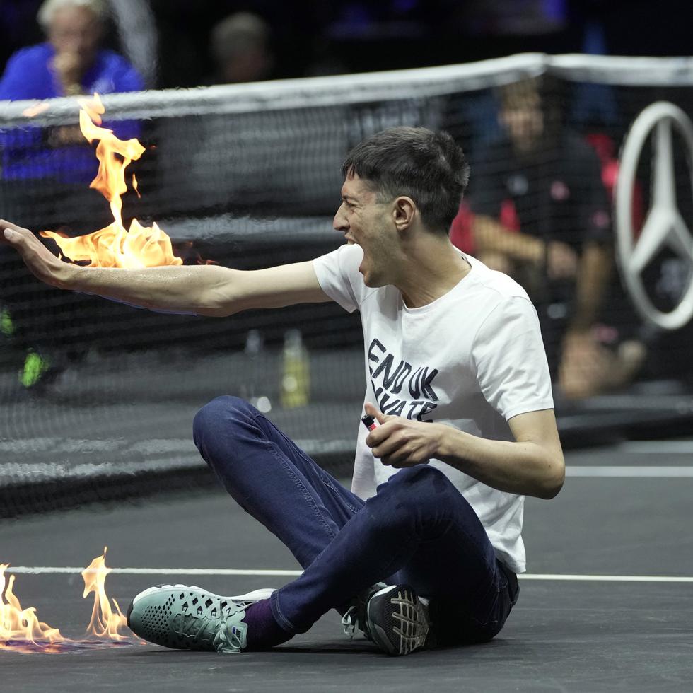 Un hombre se prende fuego en un brazo durante su protesta en el partido entre Diego Schwartzman y Stefanos Tsitsipas, en el evento de tenis Copa Laver en Londres, el viernes 23 de septiembre de 2022.