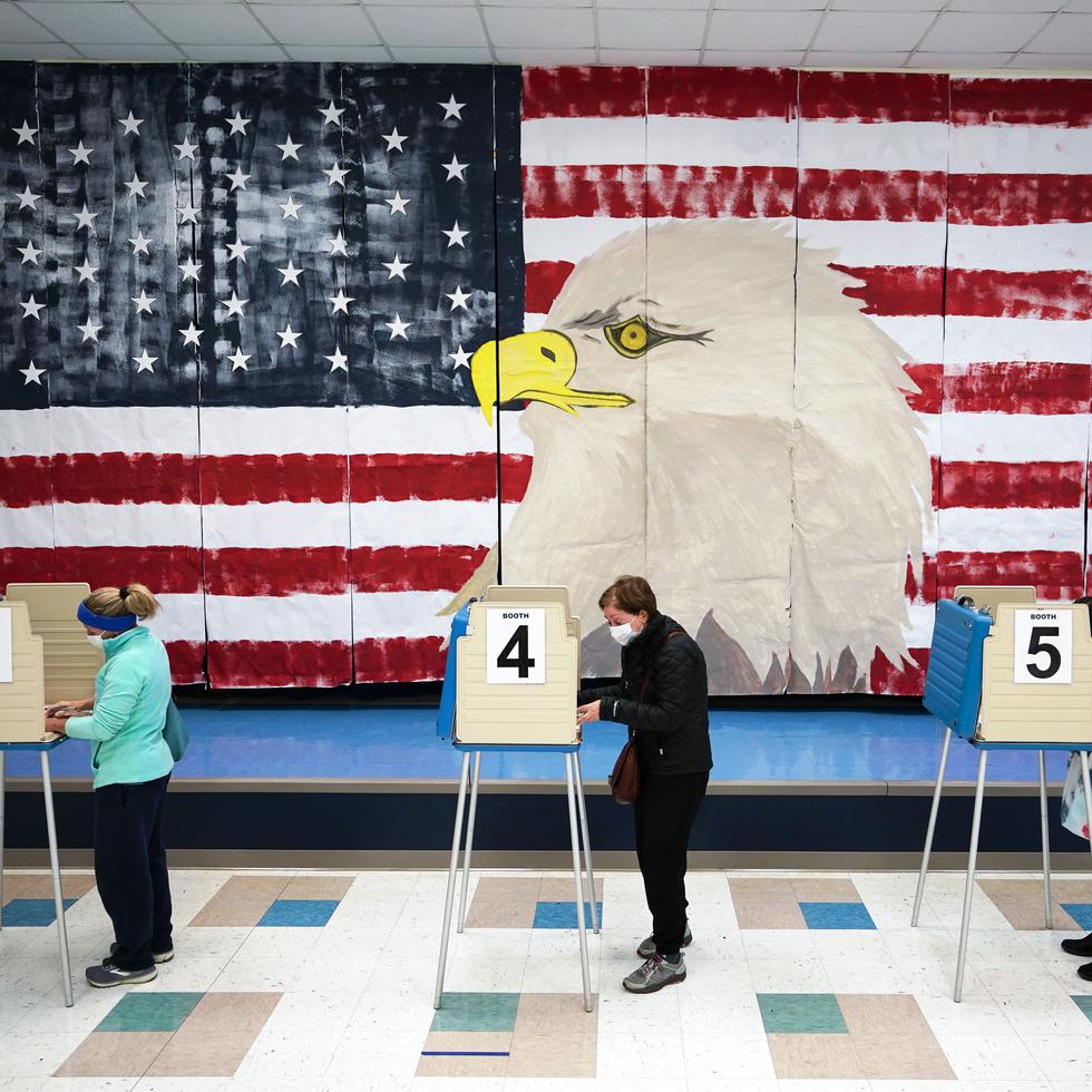 Tres personas emiten su voto al lado de un mural en la Robious Elementary School en Midlothian, Virginia.