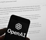 El logotipo de OpenAI se ve en un teléfono móvil frente a la pantalla de una computadora que muestra el ChatGPT.