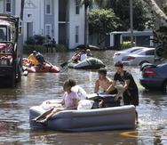 Estudiantes de la Universidad Central de Florida usan un colchón inflable para evacuar un complejo de apartamentos que quedó inundado por las lluvias del huracán Ian.