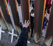 Vicky Chaidez saluda a los niños en el lado mexicano de la valla fronteriza al comienzo de un evento de Las Posadas con varias familias solicitantes de asilo en el muro fronterizo entre Estados Unidos y México.