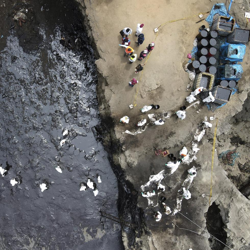 Un grupo de trabajadores continúa limpiando un derrame de petróleo en la playa Cavero, en el Callao, Perú.