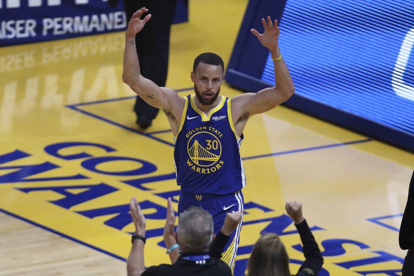 Stephen Curry de los Warriors de Golden State saluda la fanaticada.