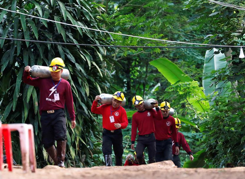 Miembros de los servicios de rescate cargan con botellas de oxígeno mientras continúan las labores de rescate de los doce menores y un adulto atrapados en una cueva en el parque de Khun Nam Nang, Tailandia. (EFE)