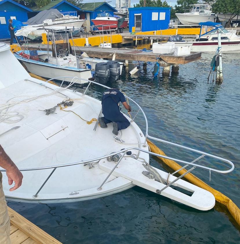 Personal de la compañía Clean Harbors, LLC., despliega material absorbente para contener y recoger el combustible diésel derramado por el barco "Ajo del País".
