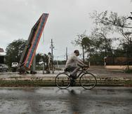 Un hombre conduce una bicicleta frente a una gasolinera destruida en Ponce. El municipio sureño volverá a ser sede del béisbol invernal en esta temporada.