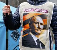 En esta imagen de archivo, un manifestante prorruso con un chaleco con la imagen del presidente de Rusia, Vladimir Putin, y las palabras "¡Patria! ¡Libertad!" durante una manifestación en Donetsk, Ucrania, el 16 de marzo de 2014. (AP Foto/Andrey Basevich, archivo)