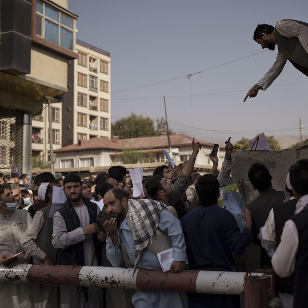 Los afganos se reúnen frente a una oficina de pasaportes del gobierno reabierta recientemente después de que los talibanes anunciaron que emitirían una acumulación de solicitudes aprobadas por la administración anterior en Kabul, Afganistán.