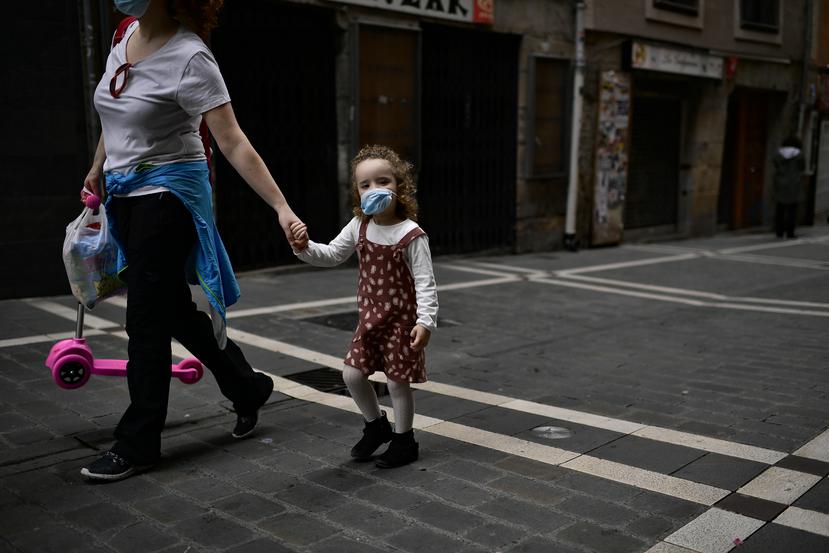 Una niña de 3 años camina junto a su madre utilizando una mascarilla por una de las calles de Pamplona, en España.