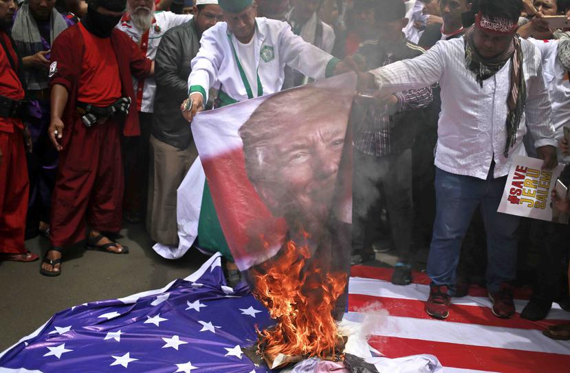 Manifestantes queman una imagen de Trump y una bandera de los Estados Unidos. (AP)