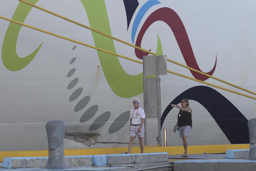 Unos turistas caminan frente al golpe que recibió el crucero.