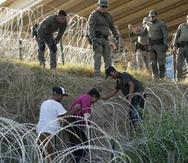 Soldados y guardias de Texas ayudan a una inmigrante que quedó atrapada en un alambre de púas después de cruzar el Río Grande desde México hacia Estados Unidos.