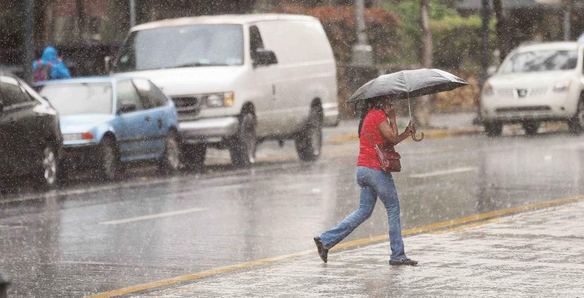 Una mujer se cubre de la lluvia con una sombrilla. (GFR Media)