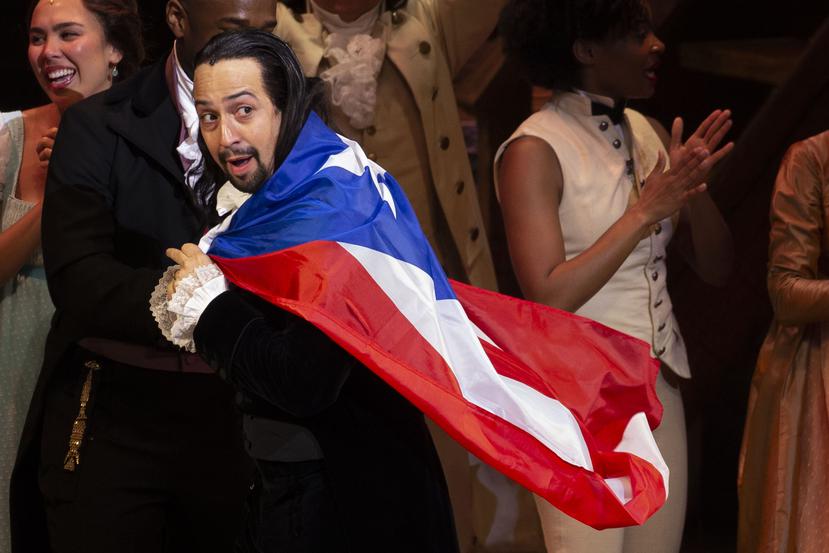 Lin-Manuel Miranda con la bandera de Puerto Rico sobre sus espaldas.