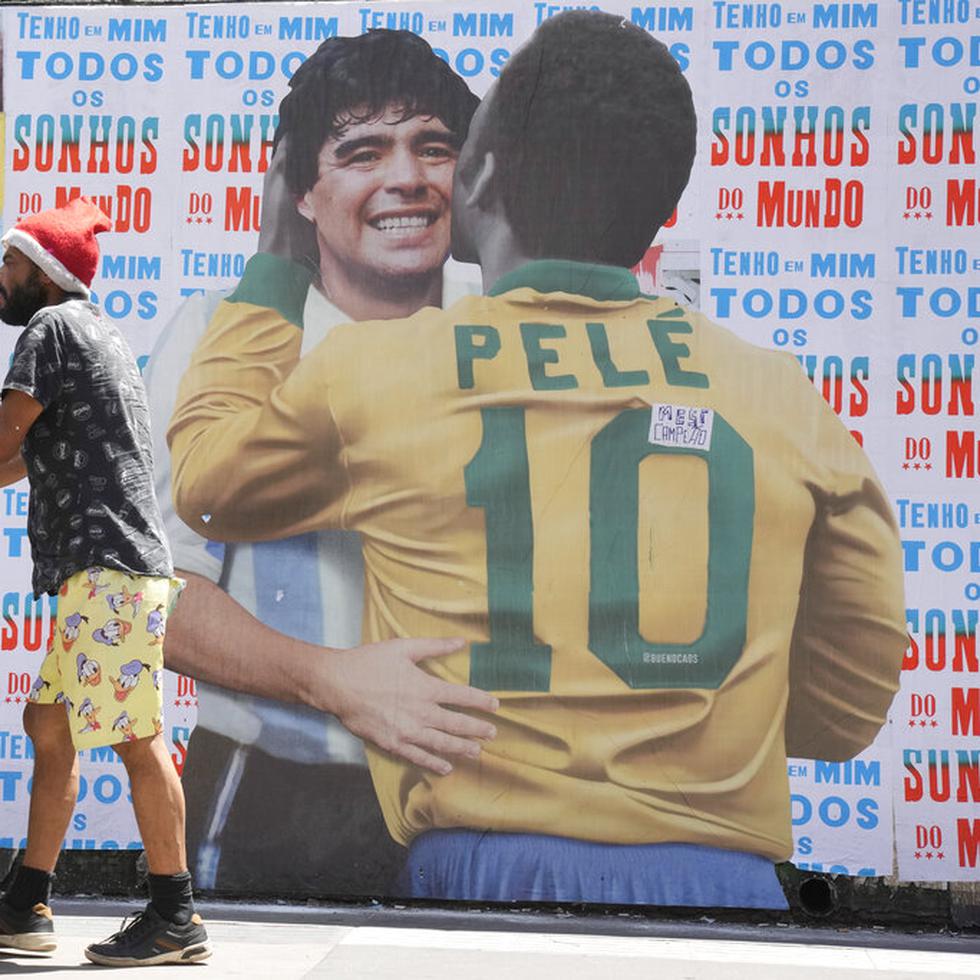 Un hombre empuja un carrito frente a un mural en el que se muestra al astro brasileño Pelé junto a la fallecida estrella del fútbol, el argentino Diego Maradona, en Sao Paulo, Brasil.