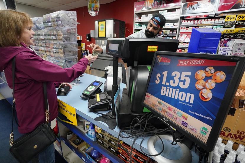En esta imagen de archivo, un cartel anuncia el pote estimado de la lotería Mega Millions mientras una persona compra un boleto en el Cranberry Super Mini Mart en Cranberry, Pensilvania, el 12 de enero de 2023.