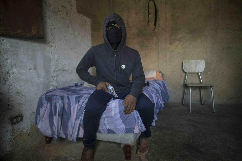 Un pandillero enmascarado apodado "El Negrito" posa para un retrato con su arma en una casa segura de su pandilla en la barriada de Petare, en Caracas, Venezuela, el lunes 13 de mayo de 2019. (AP/Rodrigo Abd)