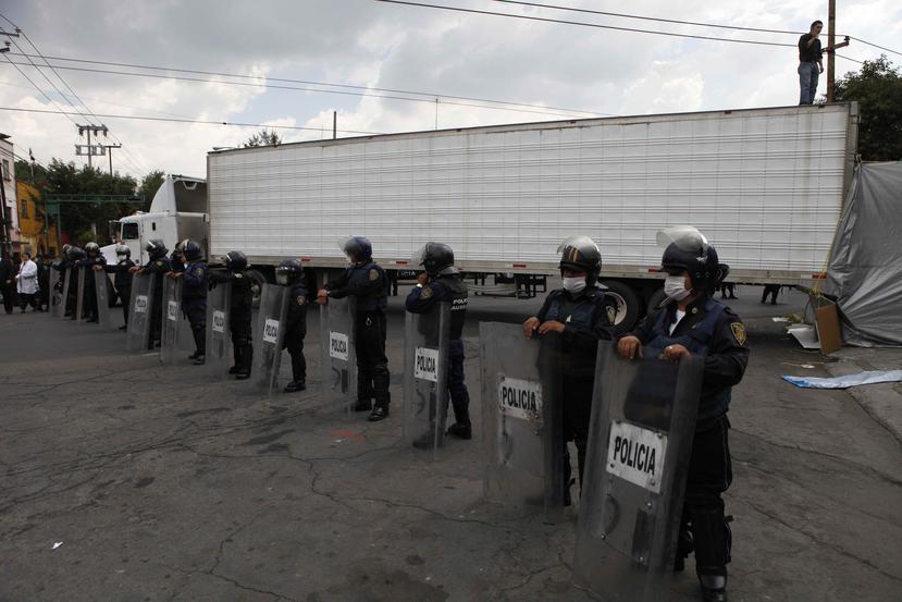 Policías portando mascarillas resguardan un camión que llegó con los cadáveres de algunos de los 72 inmigrantes que fueron asesinados en el norte de México en su camino rumbo a la frontera con Estados Unidos. (AP / Eduardo Verdugo)