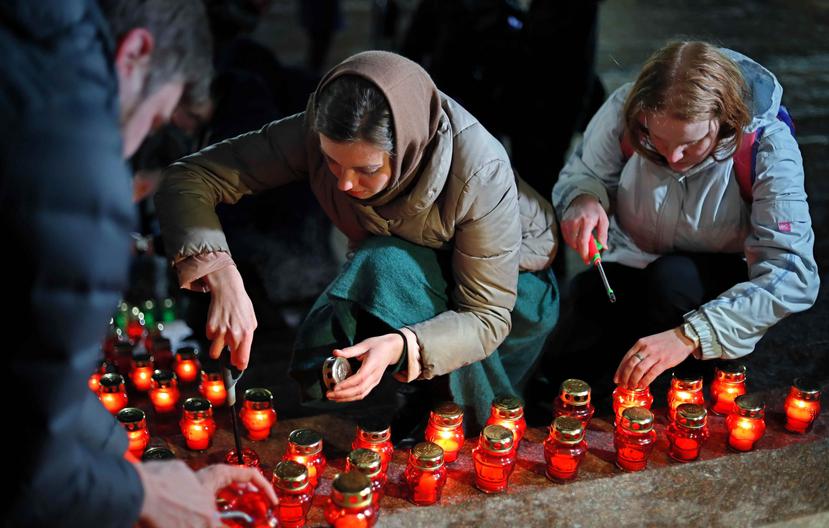Un grupo de personas muestran sus respetos con velas frente a la Catedral de Cristo Salvador de Moscú en conmemoración de las víctimas del accidente de avión, en Moscú (Rusia). (EFE/YURI KOCHETKOV)