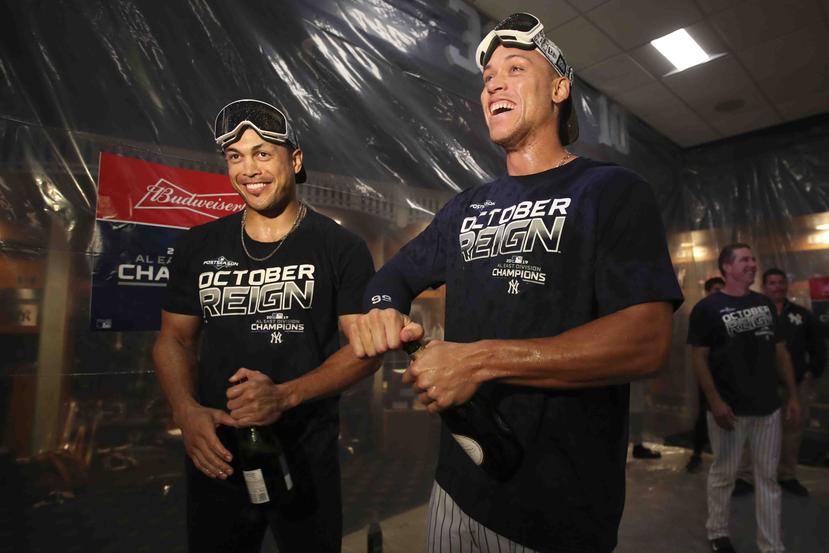 Giancarlo Stanton -izquierda- y Aaron Judge celebran con champán en mano luego de que los Yankees de Nueva York ganaran el título de la division Este el jueves. (AP)