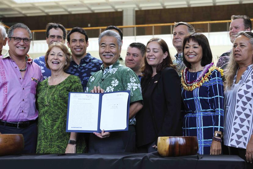 El gobernador de Hawái, David Ige (centro), junto a legisladores, muestra la medida, que firmó en Honolulu el martes. (AP)