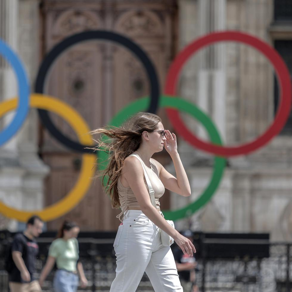 Una mujer pasa junto a los aros olímpicos afuera del ayuntamiento de París. Ucrania está incrementando esfuerzos para vetar deportistas rusos de los Juegos Olímpicos y dice que un boicot es posible.