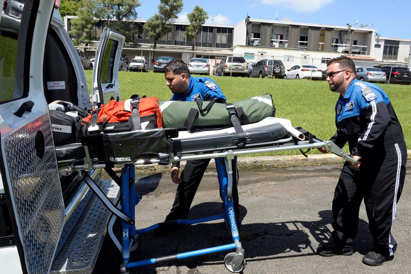 Los paramédicos Luis O. García  y Jonathan Pinto colocan una camilla en una ambulancia.