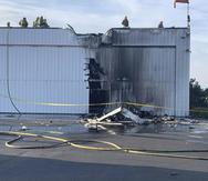 Esta fotografía proporcionada por el Departamento de Bomberos del condado San Bernardino muestra a varios bomberos examinando un hangar dañado por un avión pequeño que se estrelló contra él, el domingo 30 de julio de 2023, en el Aeropuerto Cable en Upland, California. (Departamento de Bomberos del condado San Bernardino vía AP)