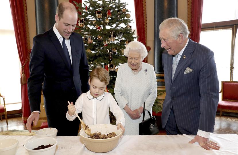 El Palacio de Buckingham difundió una foto especial en que la reina prepara postres navideños con su hijo, su nieto, y su bisnieto. (AP)