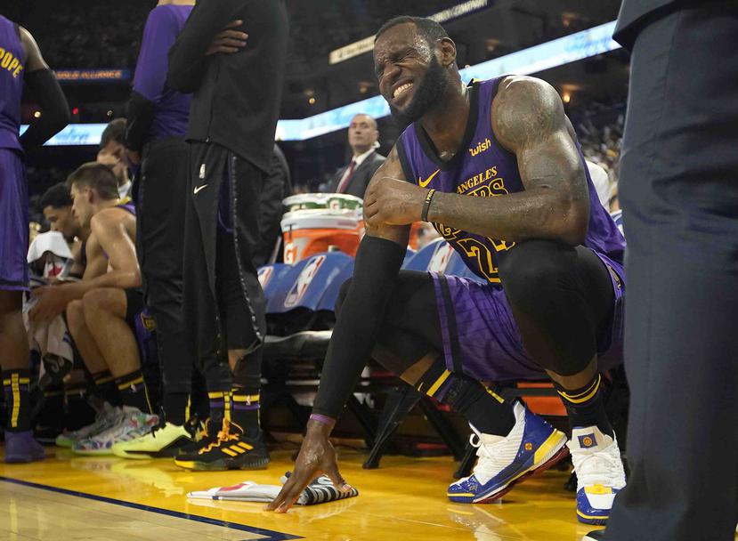LeBron James (23) hace una mueca después de lastimarse su ingle izquierda, durante la segunda mitad del juego de baloncesto de la NBA contra los Golden State Warriors, (AP)
