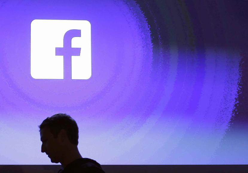 La sombra del fundador de Facebook, Mark Zuckerberg, se observa sobre una pantalla en la que se ve el logo de la empresa. (AP)
