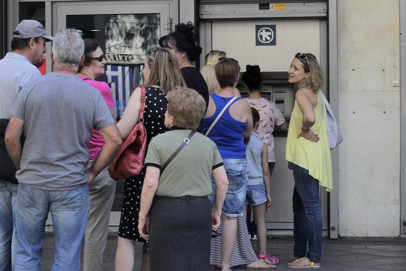 Ciudadanos atenienses hacen fila junto a un cajero de una sucursal del Banco Alfa en Atenas, Grecia.