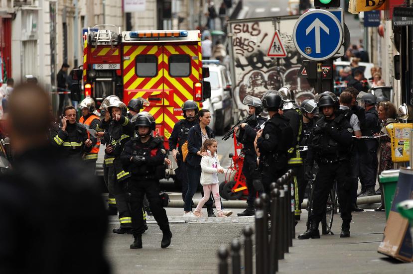 Una mujer y una niña (c) son evacuadas por las fuerzas policiales durante una toma de rehenes en la Rue des Petites Ecuries, en París. (EFE/ Yoan Valat)