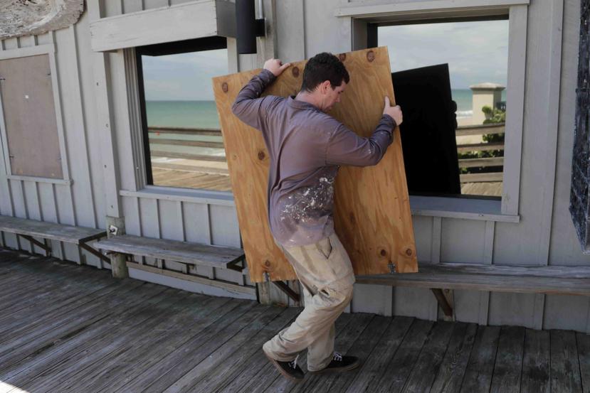 Una persona monta un panel de madera ante el posible paso del huracán Dorian por Florida. (AP)
