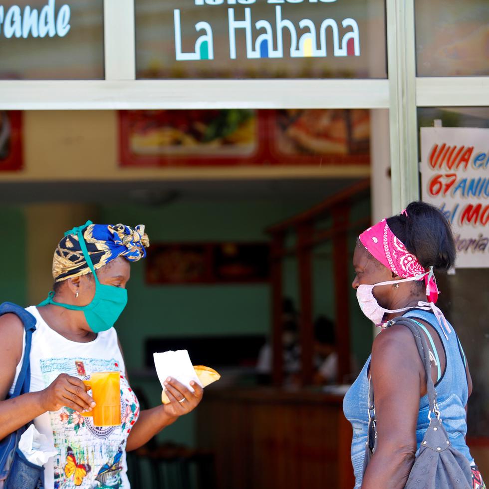 Dos mujeres conversan en la entrada de una cafetería en La Habana.