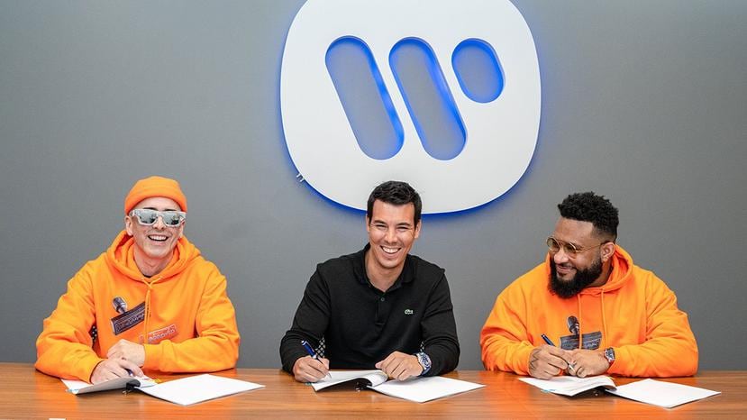 El presidente de Warner Music Latina, Alejandro Duque al centro, junto a los artistas Yandel, a la izquierda, y Ángel "El Gurú" Vera, a la derecha, durante la firma del convenio de alianza con Rapetón Approved.