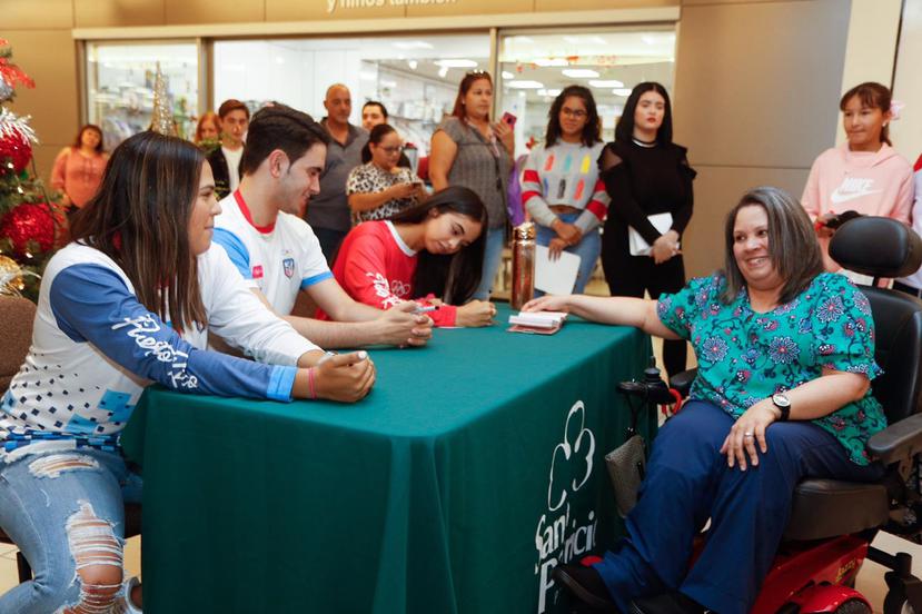 Adriana Díaz, Brian Afanador y Melanie Díaz firman un libro de la fanática Mariel González Aponte. (Suministrada)