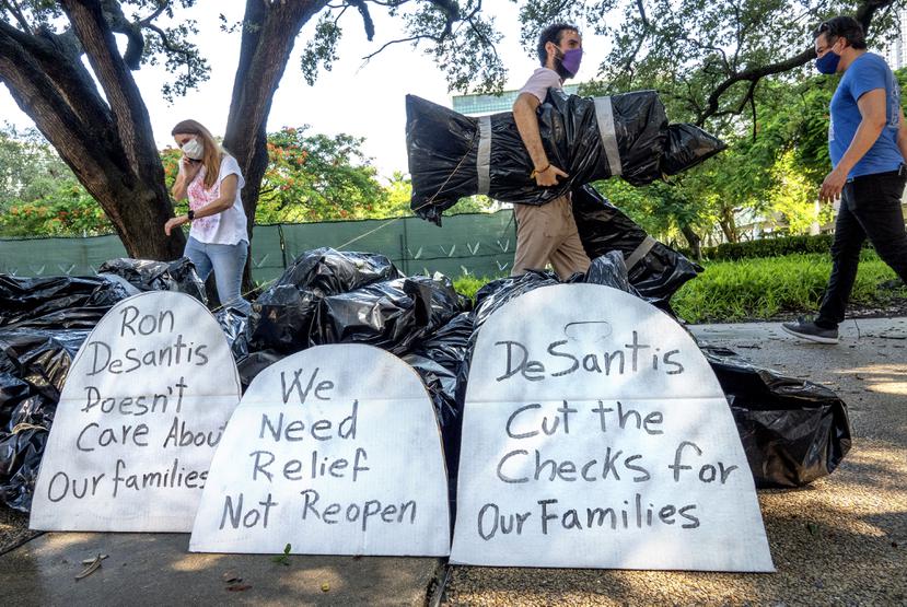 Activistas protestan utilizando bolsas de basura que aluden a los muertos por COVID-19 en momentos en que el gobernador de Florida, Ron DeSantis, insiste en la reapertura económica.