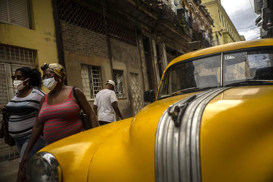 Mujeres con máscaras contra la propagación del nuevo coronavirus caminan por una calle en La Habana, Cuba, el lunes 25 de mayo de 2020. Las autoridades cubanas exigen el uso de máscaras para cualquier persona fuera de sus hogares