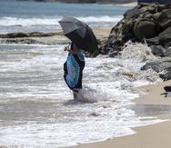 Una mujer se refresca los pies en la playa bajo una sombrilla, durante un aviso de calor extremo, el 9 de junio de 2023.