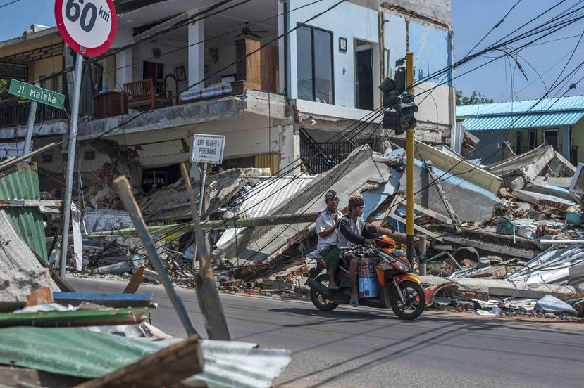 Dos hombres en una motocicleta pasan junto a construcciones arruinadas por el terremoto del domingo en Pamenang, en la isla de Lombok, Indonesia, el viernes 10 de agosto de 2018. (AP)