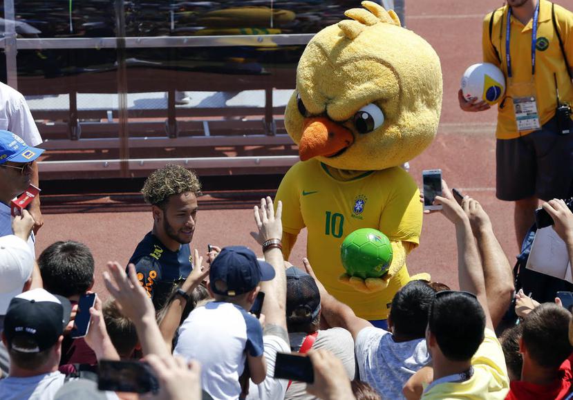 En esta foto del 12 de junio de 2018, Canarinho, la mascota de Brasil, sostiene un balón junto a Neymar, al final de un entrenamiento en Sochi, Rusia. (AP)